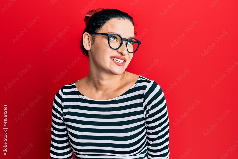 Young caucasian woman wearing casual clothes and glasses looking away to side with smile on face, natural expression. laughing confident.