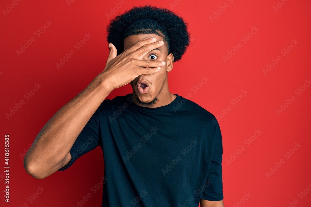 African american man with afro hair wearing casual clothes peeking in shock covering face and eyes with hand, looking through fingers afraid African american man with afro hair wearing casual clothes peeking in shock covering face and eyes with hand, looking through fingers afraid