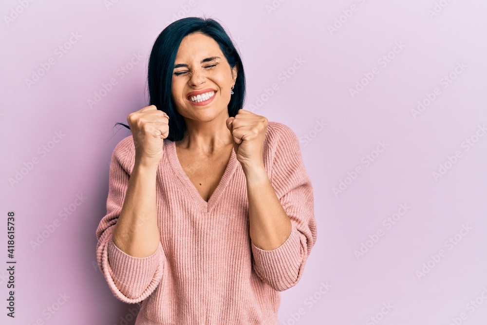 Young caucasian woman wearing casual clothes excited for success with arms raised and eyes closed celebrating victory smiling. winner concept. Young caucasian woman wearing casual clothes excited for success with arms raised and eyes closed celebrating victory smiling. winner concept.
