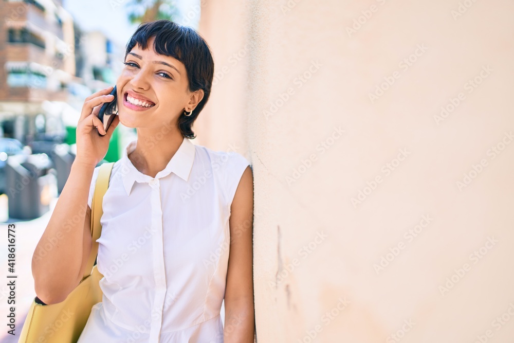 Young woman with short hair smiling happy outdoors speaking on the phone