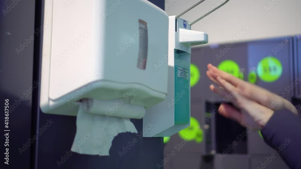 A woman uses a general antiseptic in a public place, which stands for customers at the entrance to the store. the concept of the virus and the coronavirus pandemic. and he wipes himself off with a pap A woman uses a general antiseptic in a public place, which stands for customers at the entrance to the store. the concept of the virus and the coronavirus pandemic. and he wipes himself off with a pap