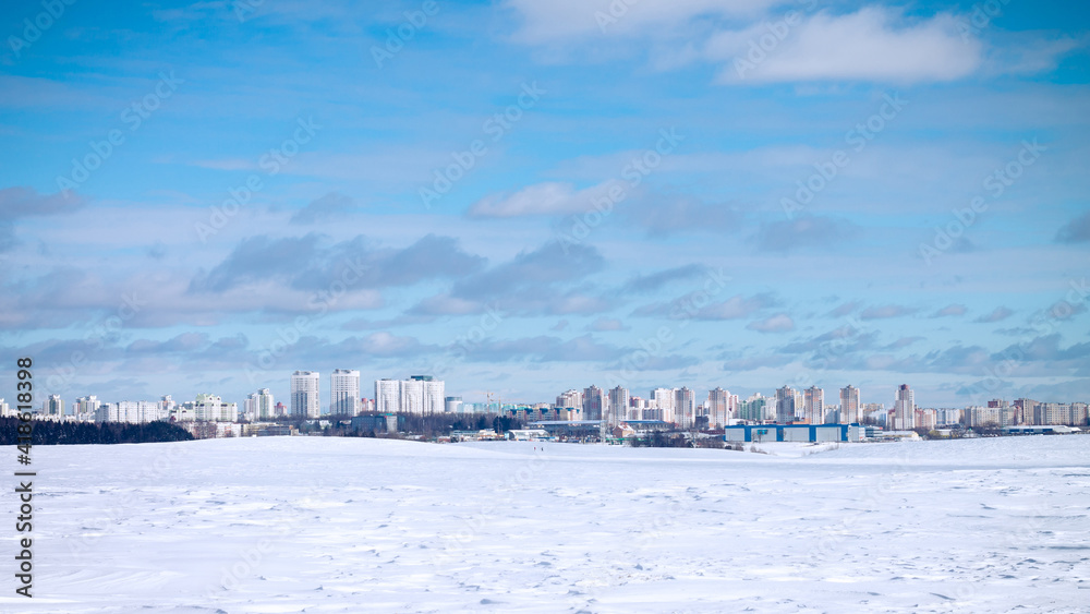 Landscape of urban high-rise buildings on background of blue sky and white snow