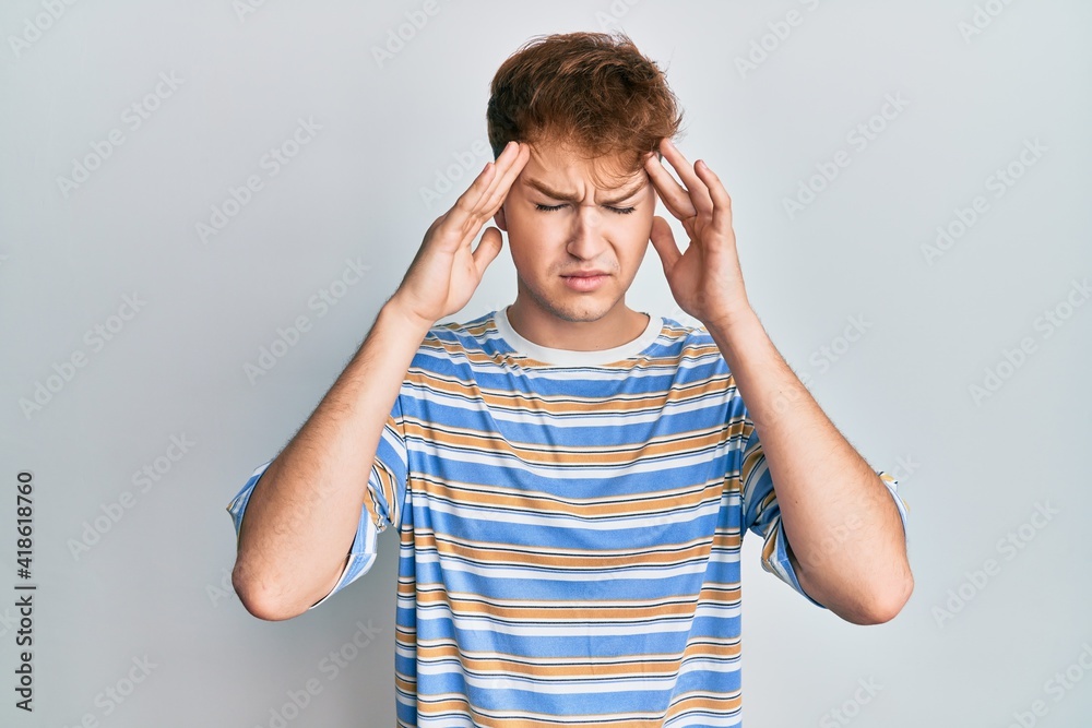 Young caucasian man wearing casual striped t shirt with hand on head, headache because stress. suffering migraine. Young caucasian man wearing casual striped t shirt with hand on head, headache because stress. suffering migraine.