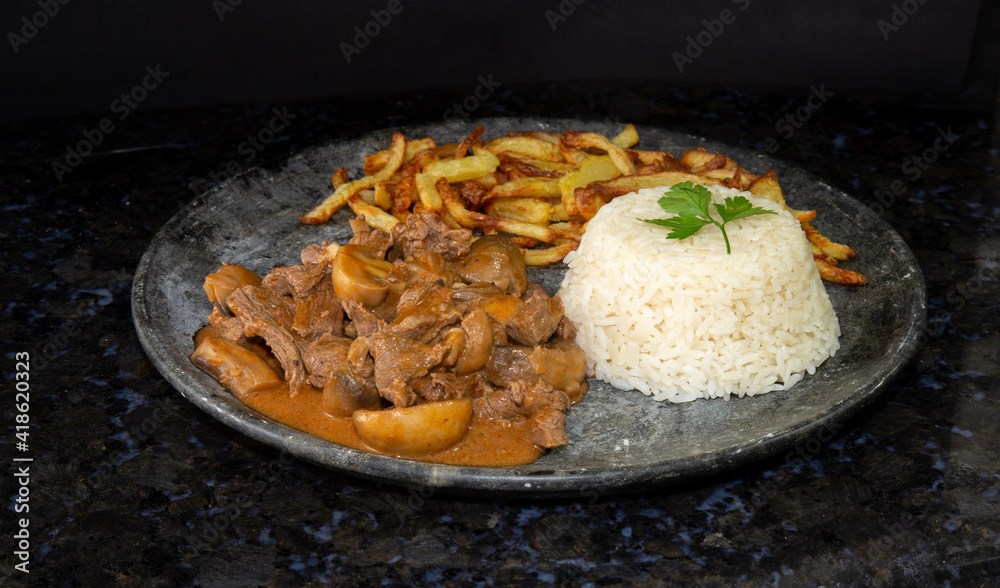 filet mignon stroganoff in an dark stone dish with white rice and french fries filet mignon stroganoff in an dark stone dish with white rice and french fries