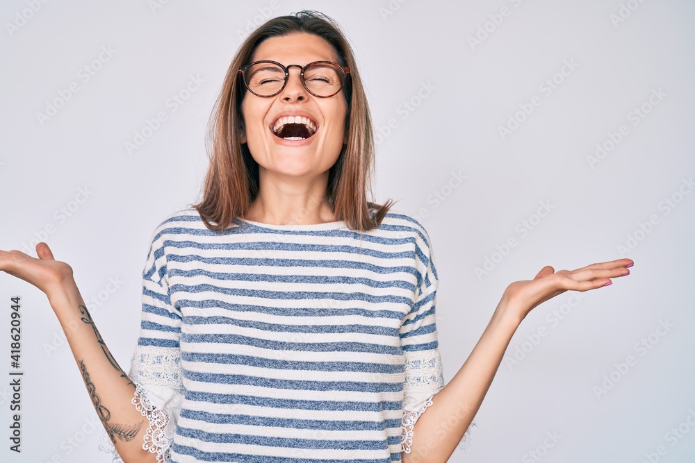 Beautiful caucasian woman wearing casual clothes and glasses celebrating mad and crazy for success with arms raised and closed eyes screaming excited. winner concept Beautiful caucasian woman wearing casual clothes and glasses celebrating mad and crazy for success with arms raised and closed eyes screaming excited. winner concept