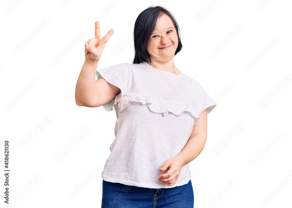 Brunette woman with down syndrome wearing casual white tshirt smiling with happy face winking at the camera doing victory sign with fingers. number two. Brunette woman with down syndrome wearing casual white tshirt smiling with happy face winking at the camera doing victory sign with fingers. number two.