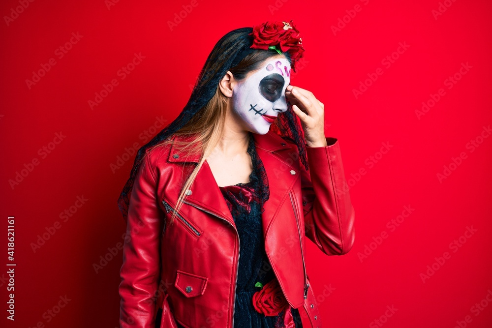 Woman wearing day of the dead costume over red tired rubbing nose and eyes feeling fatigue and headache. stress and frustration concept. Woman wearing day of the dead costume over red tired rubbing nose and eyes feeling fatigue and headache. stress and frustration concept.