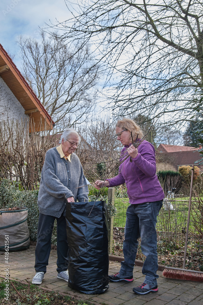Senior woman and daughter cleaning a pathway. Seasonal spring garden work. Senior woman and daughter cleaning a pathway. Seasonal spring garden work.
