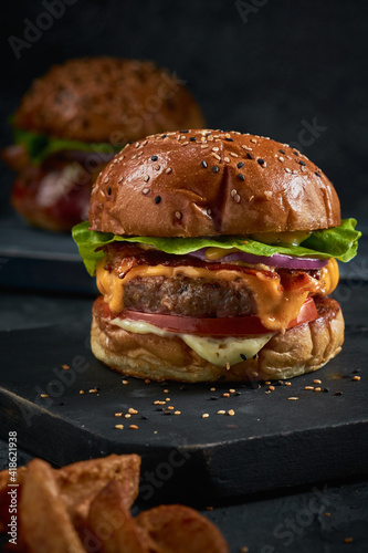  hamburguesa doble carne con tocineta queso y cebolla frita en un fondo negro 