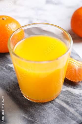 Glass of fresh tangerine juice and fruits on board