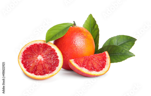 Whole and cut red oranges with green leaves on white background