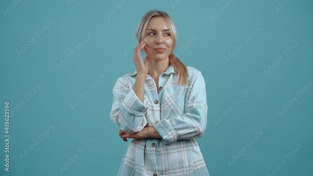 The confident young woman thinks of ideas, raising a finger up, at the end she smiles and winks. Beautiful mature young woman, blonde, in a shirt, blue. Isolated on blue background, Concept of life The confident young woman thinks of ideas, raising a finger up, at the end she smiles and winks. Beautiful mature young woman, blonde, in a shirt, blue. Isolated on blue background, Concept of life