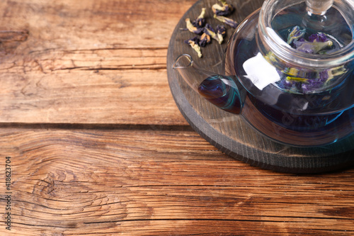 Organic blue Anchan in glass pot on wooden table, above view with space for text. Herbal tea