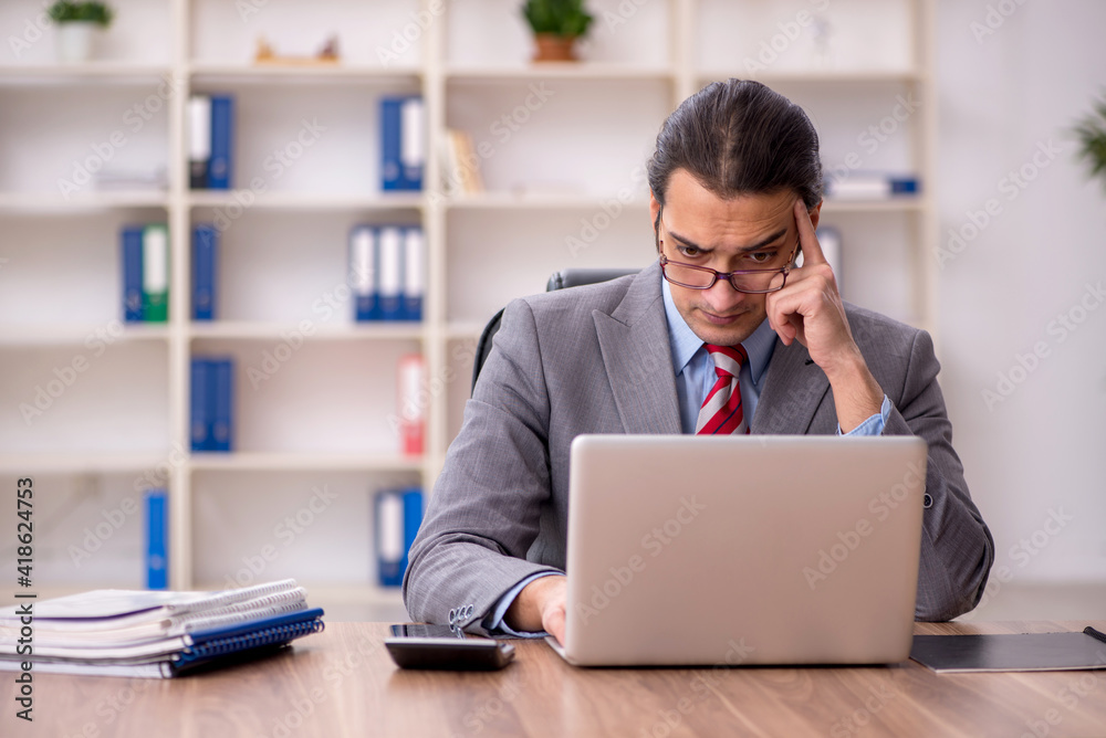 Young male employee sitting at workplace