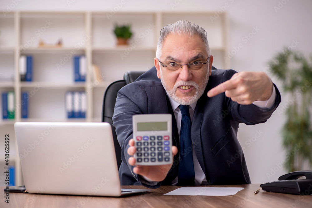 Old male bookkeeper sitting in the office Old male bookkeeper sitting in the office