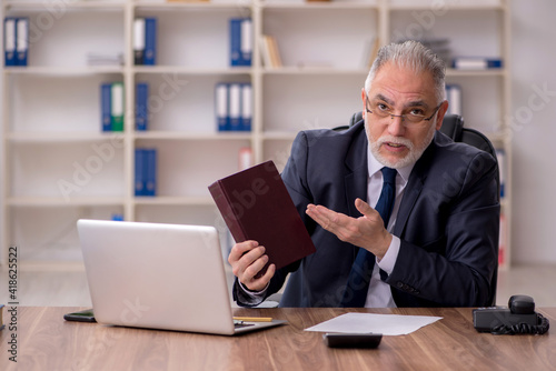 Old male employee holding book at workplace © Elnur