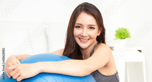 Portrait of sport asian woman in sportswear sitting relax and practicing yoga and do fitness exercise look at camera at home.Diet concept.Fitness and healthy lifestyle