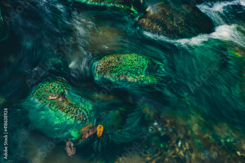 Clear water rapids with green moss grow on the rocks because of the drop in river water levels in the summer.