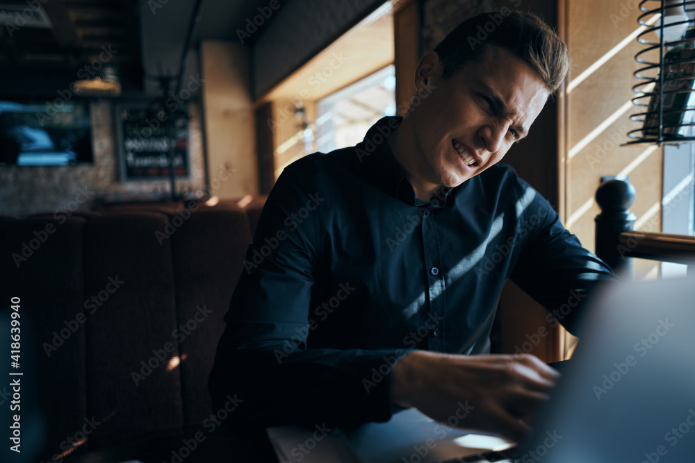 A business man in a cafe is sitting at a table while working in front of a laptop