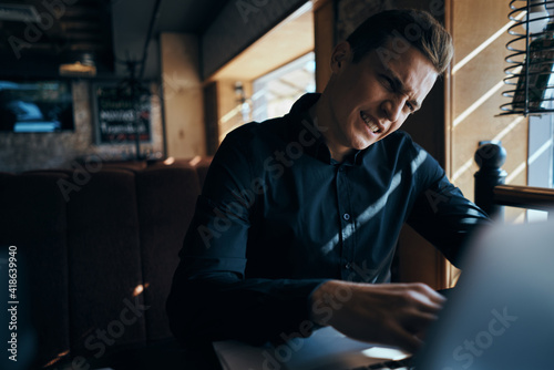 A business man in a cafe is sitting at a table while working in front of a laptop