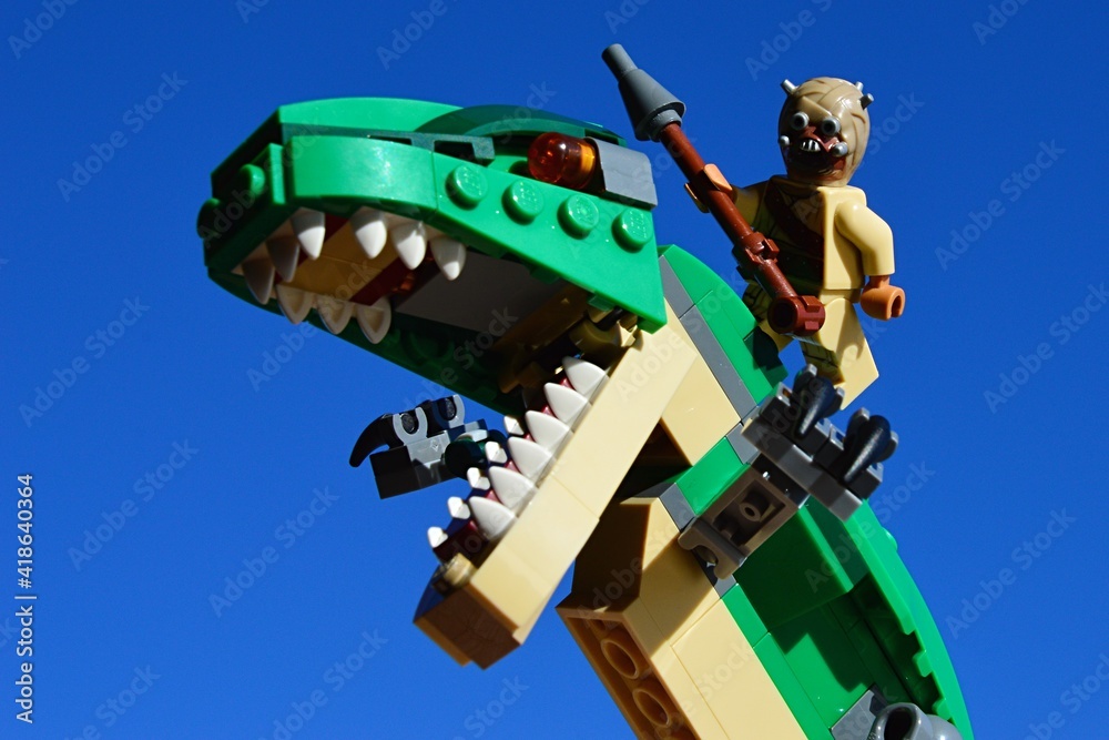 Obraz premium LEGO Star Wars Tusken Raider riding on Tyrannosaurus Rex from LEGO Creator series, blue skies background.