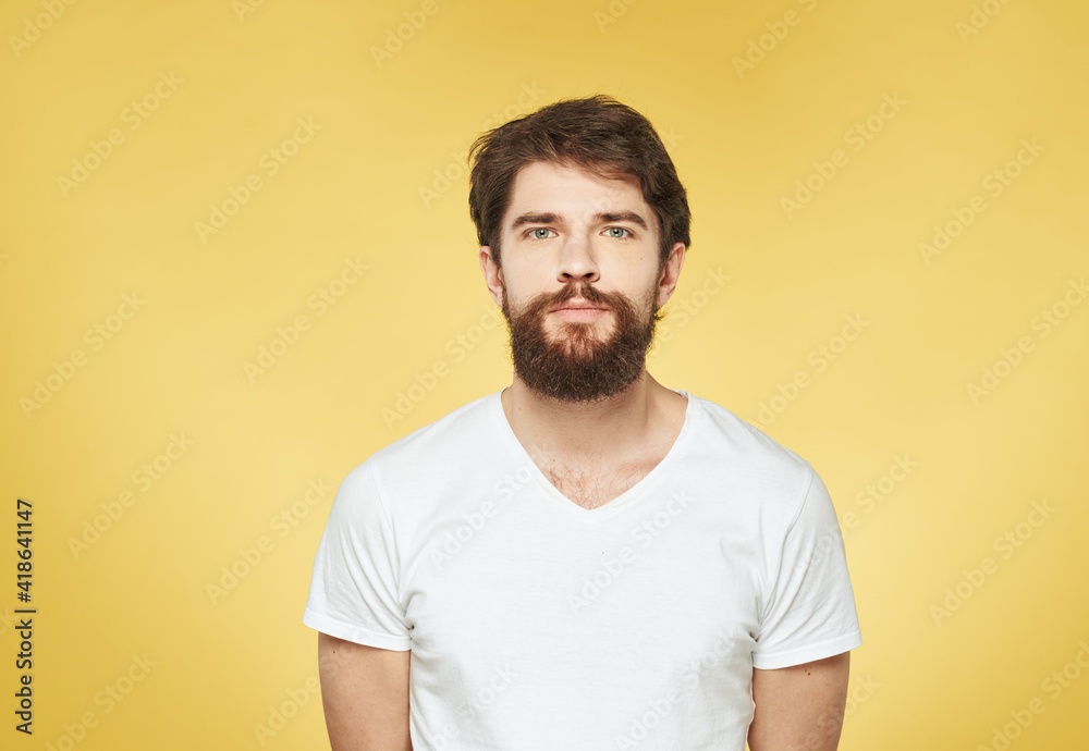 Brunette man on a yellow background in a white t-shirt cropped view Brunette man on a yellow background in a white t-shirt cropped view