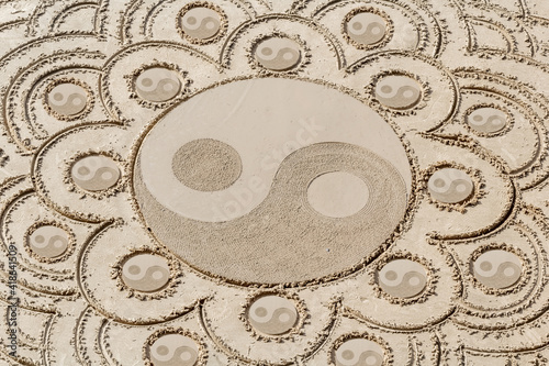 Motifs yin yang tracés sur le sable de plage 