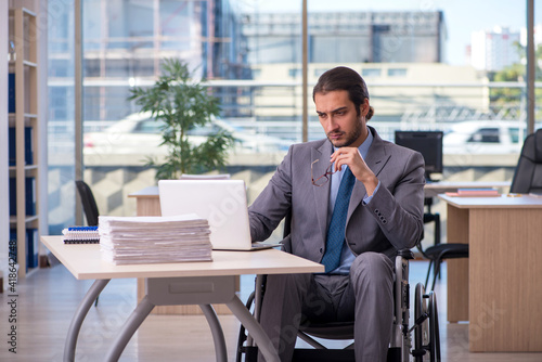 Young male employee in wheel-chair working in the office