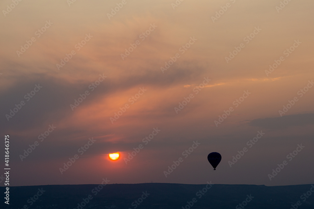Hot air balloons over the rocks on sunrise with empty blue sky