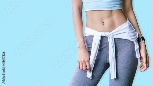 Foto Portrait of sporty young woman with muscular body, posing against a cyan background and space, Six pack