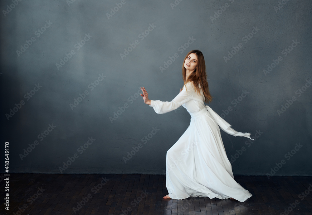 Charming lady in a white dress on a gray background dance gesticulating with her hands model Charming lady in a white dress on a gray background dance gesticulating with her hands model