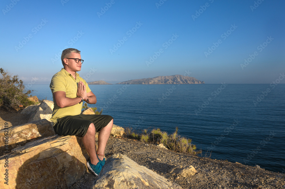 Man meditating on rock in mountain
