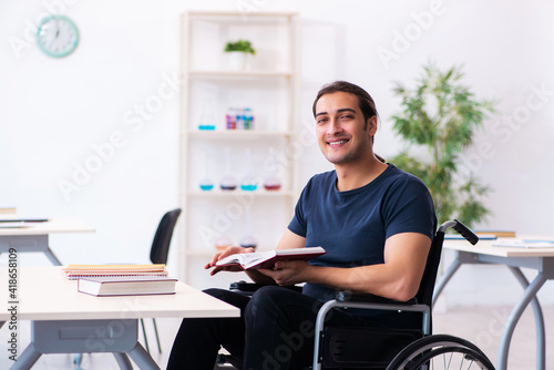 Young male student in wheel-chair preparing for exams