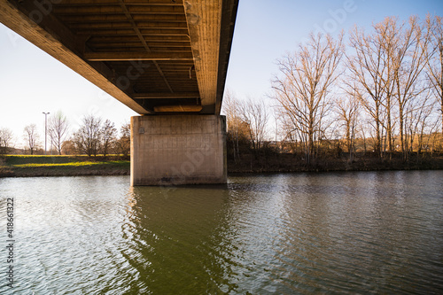 A closeup shot of an old bridge above the river surrounded by trees