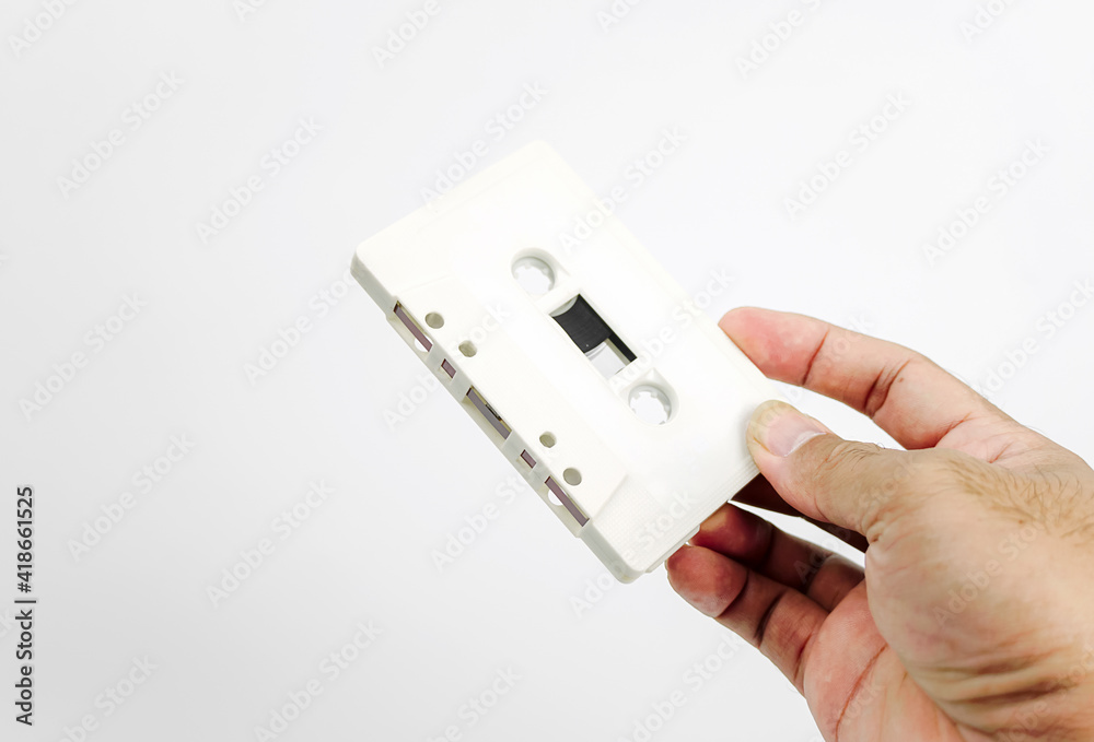 Hand holding cassette tape isolated on white background. Old cassette tape audio isolated on white. Hand holding cassette tape isolated on white background. Old cassette tape audio isolated on white.