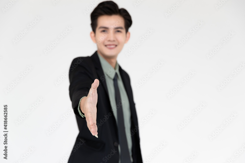 Portrait of young and handsome Asian businessman in a black suit pose with smile face and giving hand for shake with self-confidence to camera isolated on white background Portrait of young and handsome Asian businessman in a black suit pose with smile face and giving hand for shake with self-confidence to camera isolated on white background