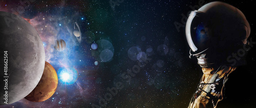 Fototapeta Naklejka Na Ścianę i Meble -  Concept of an astronaut looking up into the stars and solar system planets. Sci-fi space exploration collage, elements of this image furnished by NASA.