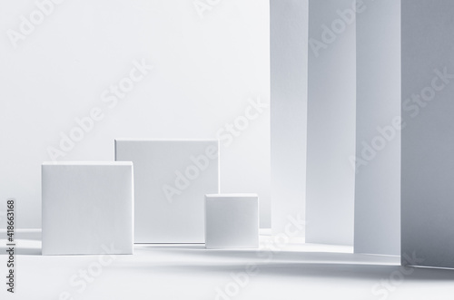 White square podiums in sunlight with shadow on white striped perspective background. Trend fashion showcase for cosmetic products, goods, shoes, bags, watches.
