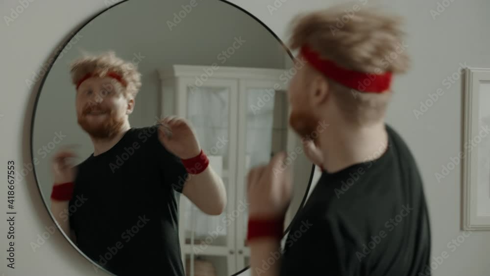 CRASH ZOOM Portrait of funny Caucasian man dancing in front of the mirror after working out, cheering himself. Motivation, self confidence concept