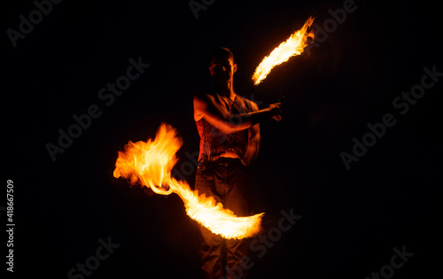 Fakir show. Happy man manipulate with burning poi. Fire fakir perform dangerous tricks. photo