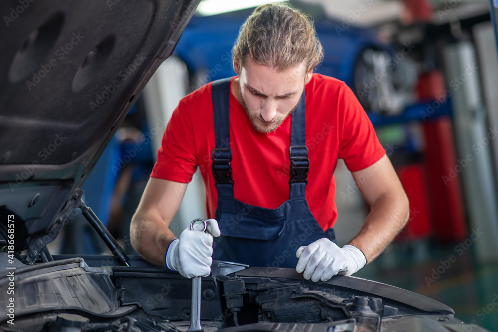 Concentrated repairman working in hood of car Concentrated repairman working in hood of car