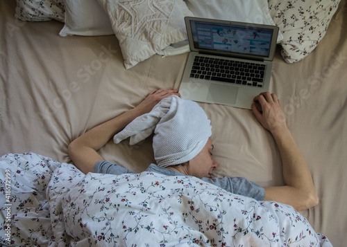 Woman in bed with laptop using internet in online service