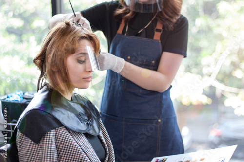 A cute young woman caucasian  looking at example hair style catalog before hair coloring.