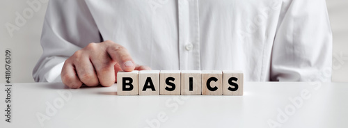 Businessman pressing his finger on the wooden cubes with the word basics. photo