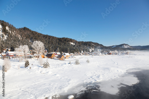 Fototapeta Naklejka Na Ścianę i Meble -  Top view of the winter Altai, the village of Artybash on the bank of the Biya River and the mountains covered with forest. Altai Republic, Russia