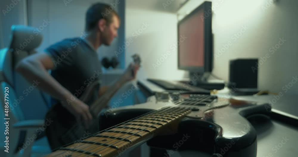 handsome man writes electronic music at home at the table in front of the monitor handsome man writes electronic music at home at the table in front of the monitor
