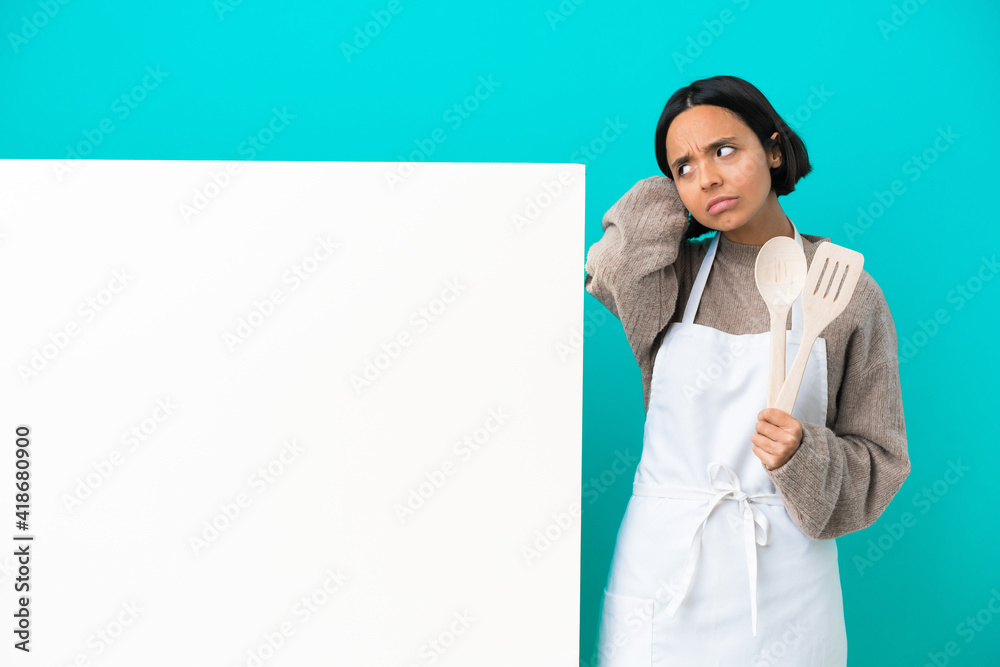 Young mixed race cook woman with a big placard isolated on blue background having doubts while scratching head Young mixed race cook woman with a big placard isolated on blue background having doubts while scratching head