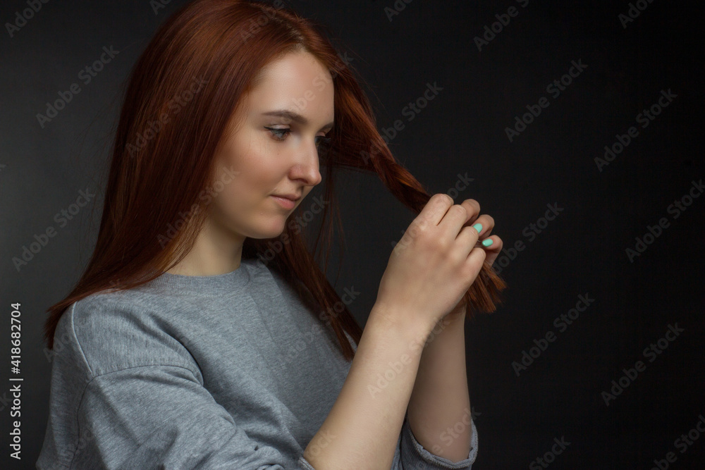 Obraz premium Red-haired young girl on black background in a gray T-shirt