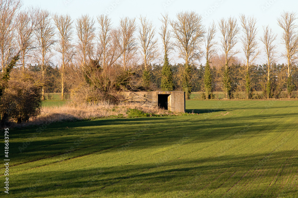 Obraz premium war time pillar box isolated on field, world war 2 anti-tank bunker/ pillbox. These were used for the defence of the UK.