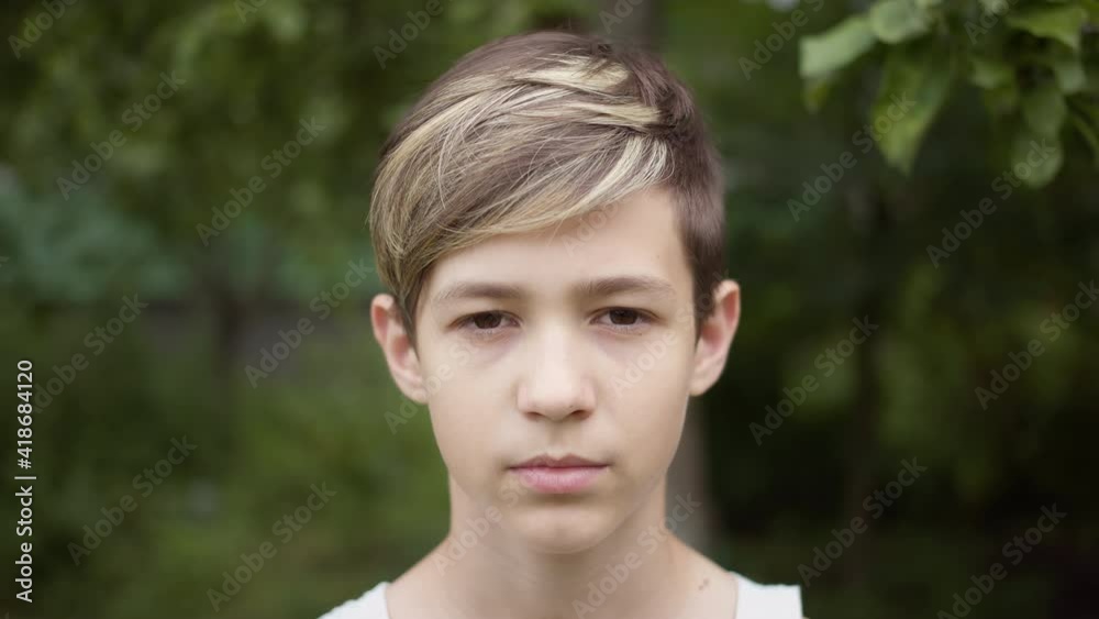 portrait of a boy with a stylish hairstyle looking at the camera and smiling outdoors portrait of a boy with a stylish hairstyle looking at the camera and smiling outdoors